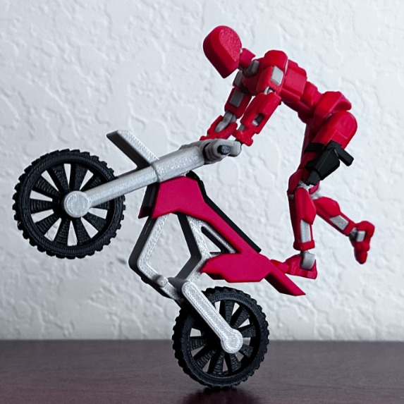 Dummy rojo haciendo un caballito con una moto